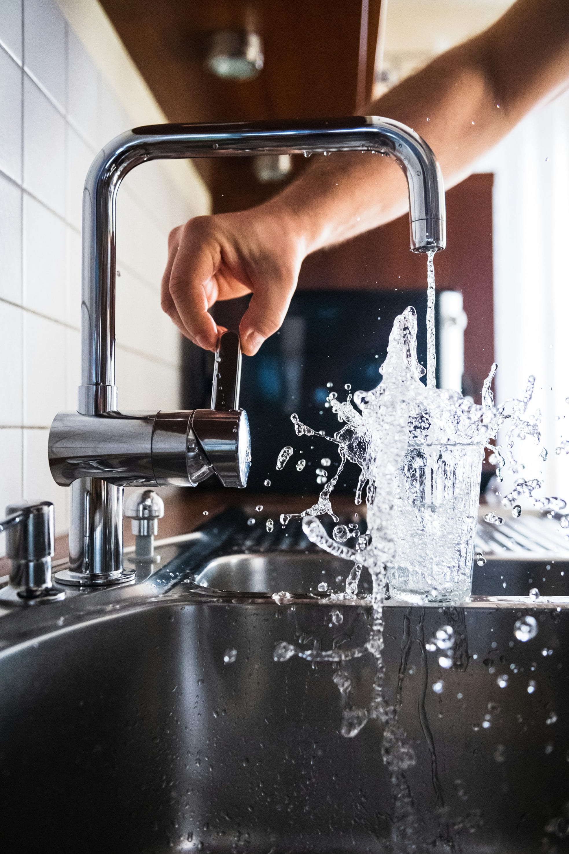 Hand filling glass of water from kitchen faucet

